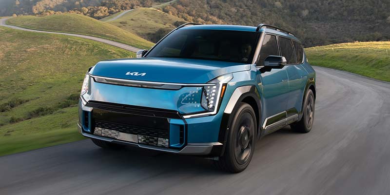 Blue Kia EV9 SUV driving on road